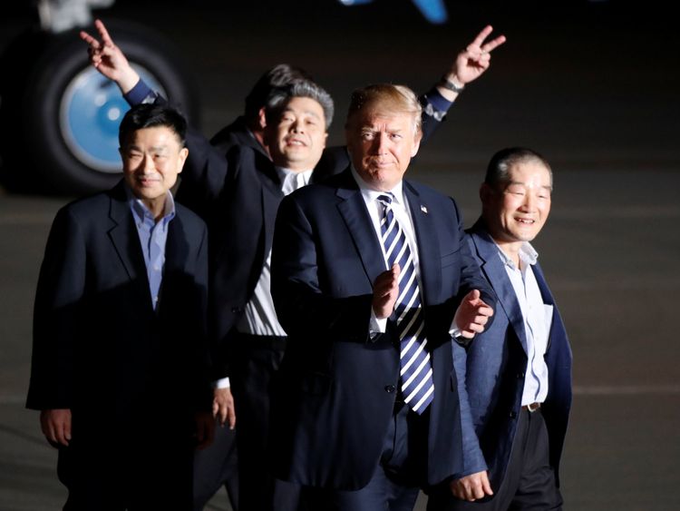 The three Americans formerly held hostage in North Korea gesture next to U.S.President Donald Trump, upon their arrival at Joint Base Andrews