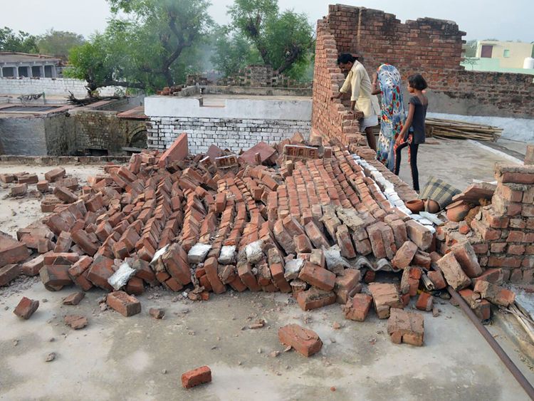 Indian residents look at a wall damaged by high winds during a major dust storm in Agra district in northern India&#39;s Uttar Pradesh state