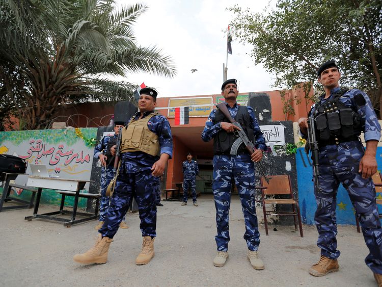 Iraqi security forces stand guard outside a polling station in Baghdad