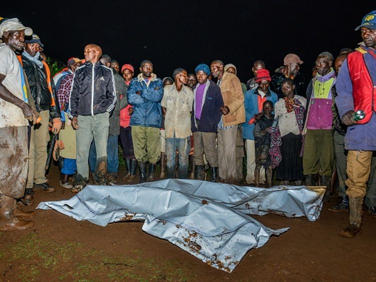 Rescuers and locals stand around two recovered bodies after the flooding