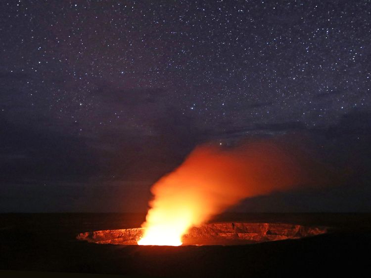 Stars shine above as a plume rises from the Halemaumau crater, illuminated by glow from the crater's lava lake, within the Kilauea volcano summit at the Hawaii Volcanoes National Park on May 9, 2018