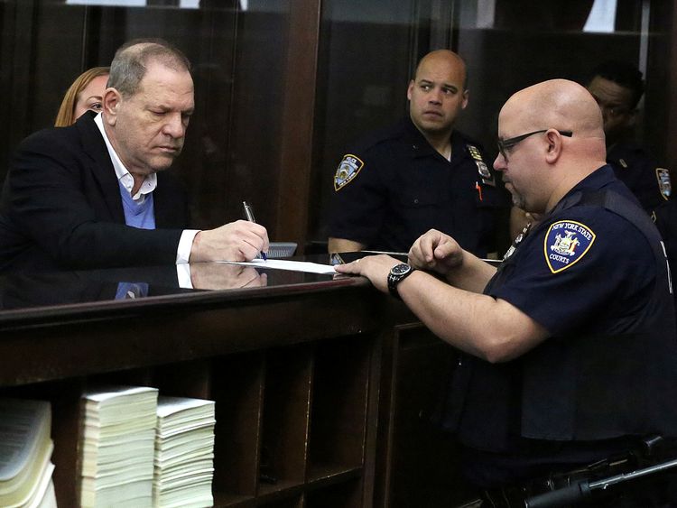 Film producer Harvey Weinstein signs papers inside Manhattan Criminal Court during his arraignment in Manhattan in New York