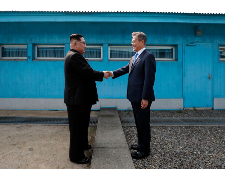 Kim Jong Un (L) and Moon Jae-in (R) shake hands over the military demarcation line