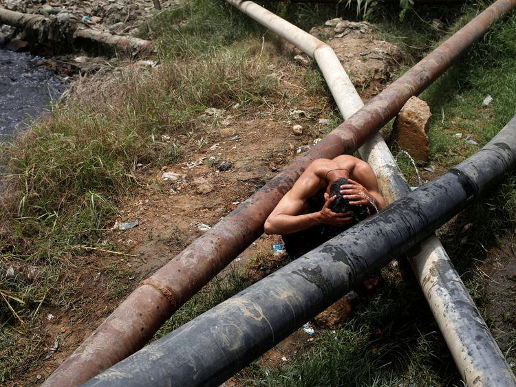 A man cools off near a leaking water pipe