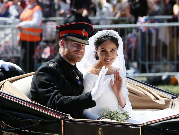 Prince Harry and Meghan Markle ride in an open-topped carriage