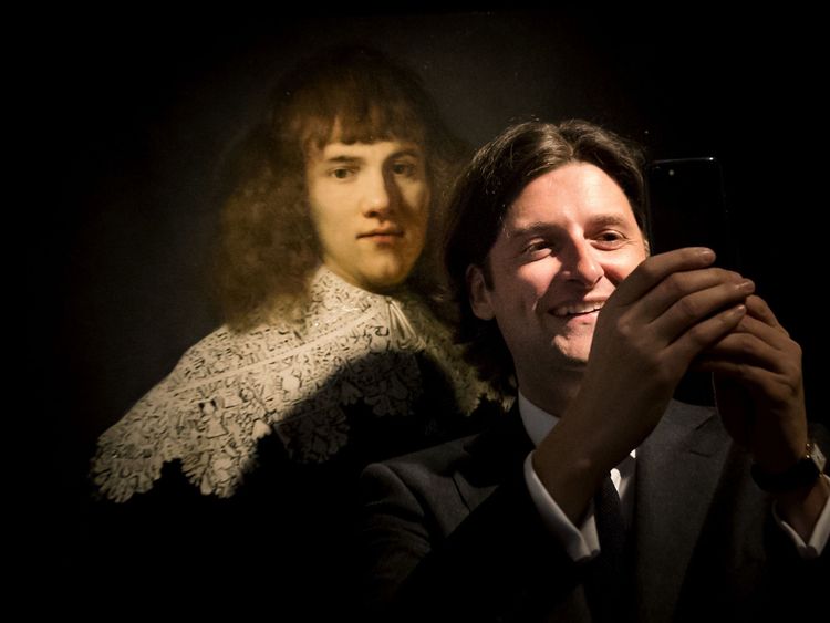 Amsterdam art dealer and historian Jan Six (R) takes a 'selfie' as he stands beside 'Portrait of a Young Gentleman' by Rembrandt van Rijn