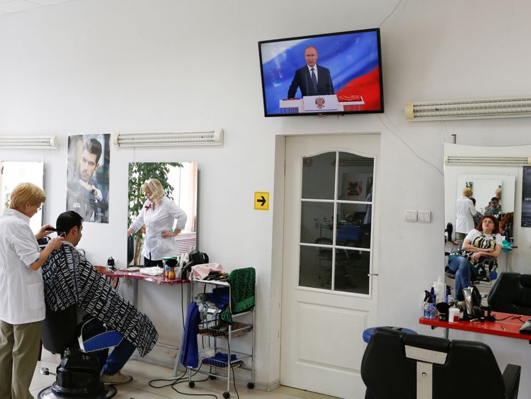 A hairdresser, who watches a ceremony to inaugurate Vladimir Putin as President of Russia, is reflected in a mirror at a hair design salon in Stavropol, Russia May 7, 2018. REUTERS/Eduard Korniyenko