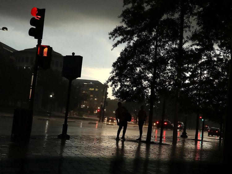 People stand under trees as a severe thunderstorm passes over the US Capitol in Washington DC