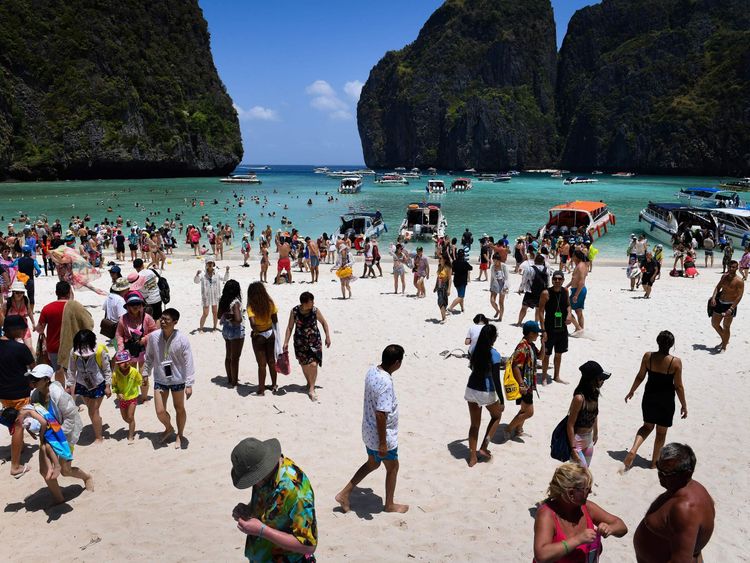 This photo taken on April 9, 2018 shows a crowd of tourists on the Maya Bay beach, on the southern Thai island of Koh Phi Phi. Across the region, Southeast Asia's once-pristine beaches are reeling from decades of unchecked tourism as governments scramble to confront trash-filled waters and environmental degradation without puncturing a key economic driver. / AFP PHOTO / Lillian SUWANRUMPHA / TO GO WITH AFP STORY 'THAILAND-INDONESIA-PHILIPPINES-TOURISM-ENVIRONMENT' by Lillian SUWANRUMPHA with Joe