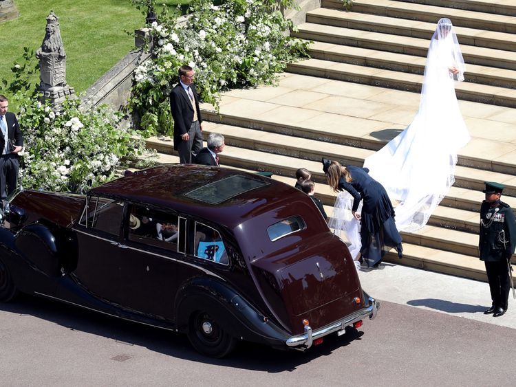 Clare Waight Keller assisting the bride with her train on the steps of St George's Chapel