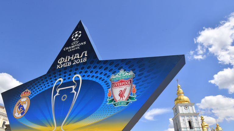 A woman takes a picture as she walks past a star shaped billboard announcing the 2018 UEFA Champions League final in the city centre of Kiev 