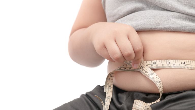 fat child check out his body fat with measuring tape isolated on white background, obesity or diet concept