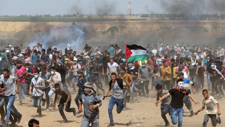 Palestinian demonstrators run for cover from tear gas fired by Israeli forces 