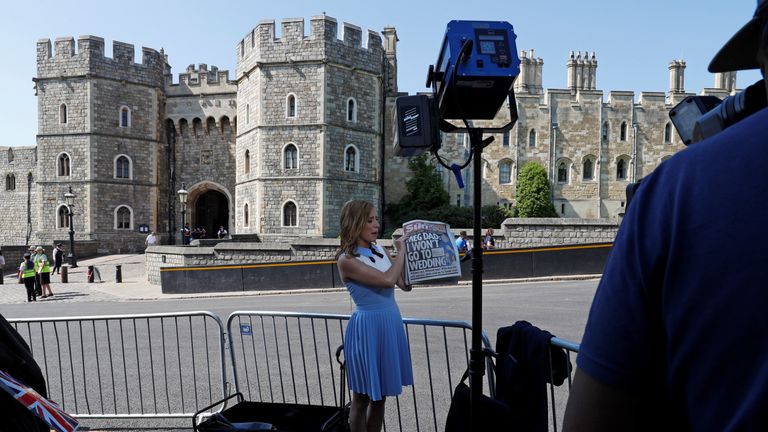 A television reporter for the US network CNN, holds up copies of today&#39;s British newspapers leading with a story of Meghan Markle&#39;s father Thomas Markle, opposite the Henry VII Gate of Windsor Castle in Windsor