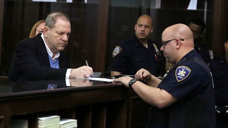 Film producer Harvey Weinstein signs papers inside Manhattan Criminal Court during his arraignment in Manhattan in New York