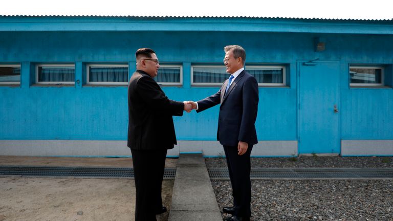 Kim Jong Un (L) and Moon Jae-in (R) shake hands over the military demarcation line