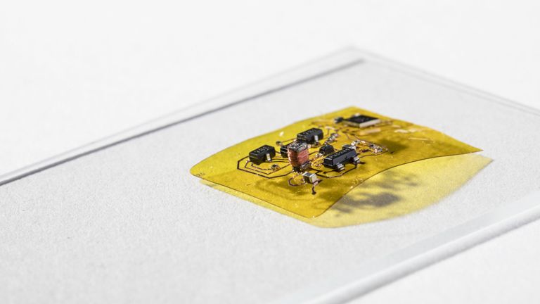 To make RoboFly wireless, the engineers designed a flexible circuit (yellow) with a boost converter (copper coil and black boxes at left) that boosts the seven volts coming from the photovoltaic cell into the 240 volts needed for flight. This circuit also has a microcontroller brain (black square box in the top right) that lets RoboFly control its wings. Credit: Mark Stone/University of Washington
