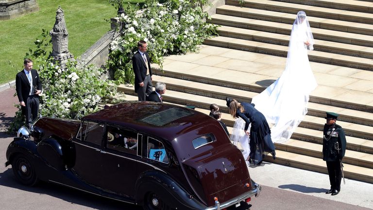Clare Waight Keller assisting the bride with her train on the steps of St George&#39;s Chapel