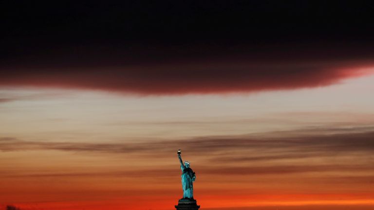 The sun sets behind the Statue of Liberty after a rain storm in New York, U.S