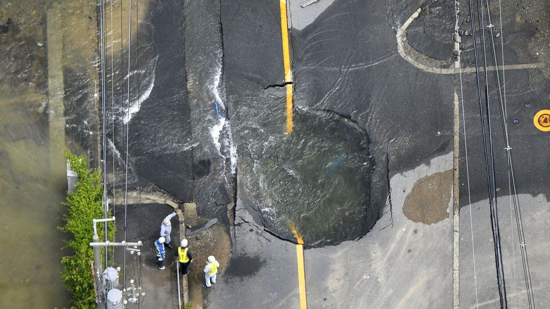 Water flows out from cracks in a road damaged by the earthquake