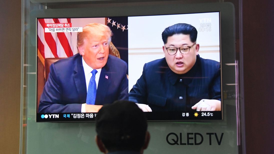 A man watches a television news screen showing US President Donald Trump (L) and North Korean leader Kim Jong Un (R), at a railway station in Seoul on May 25, 2018