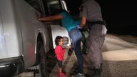 A toddler cries as her mother is searched at the border