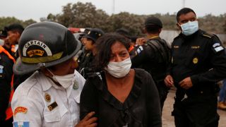 A woman is comforted by a firefighter while mourning for her missing relatives