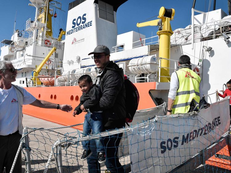 A migrant and his child disembark from the MV Aquarius last month