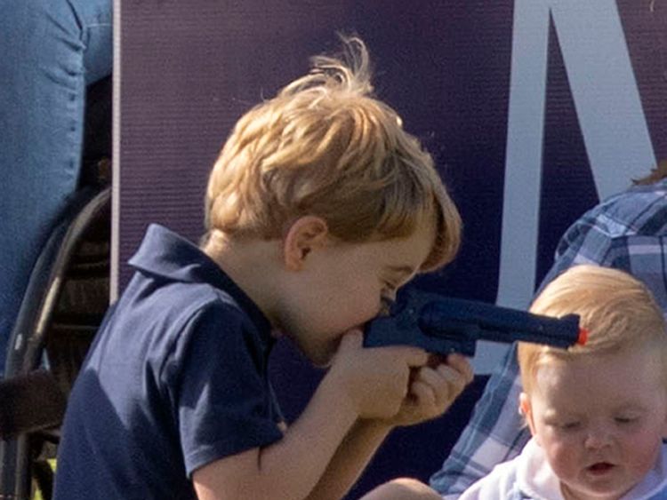 Prince George plays with a toy gun as he sits with his mother the Duchess of Cambridge and other members of the royal family, whilst his father the Duke of Cambridge takes part in the Maserati Royal Charity Polo Trophy at the Beaufort Polo Club, Downfarm House, Westonbirt, Tetbury. 