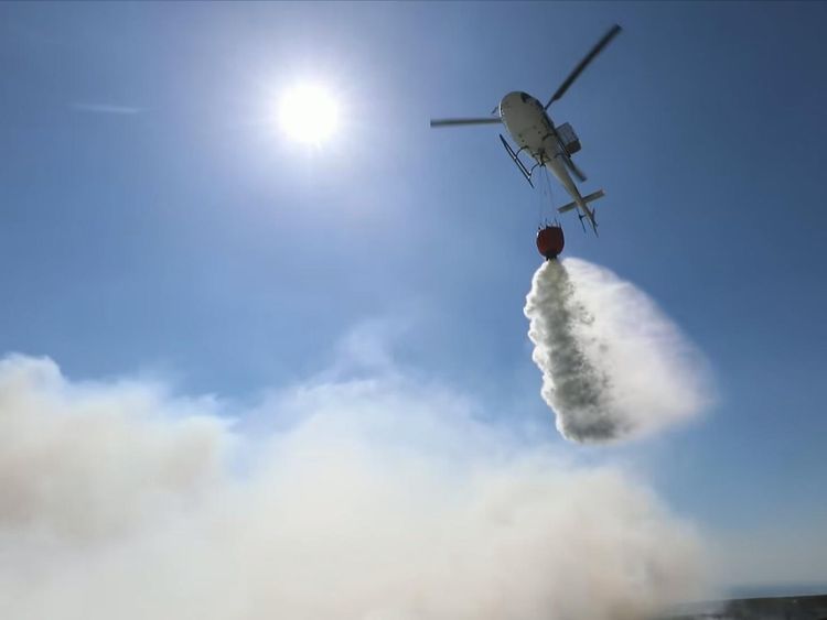 A helicopter drops water on the fire from the air