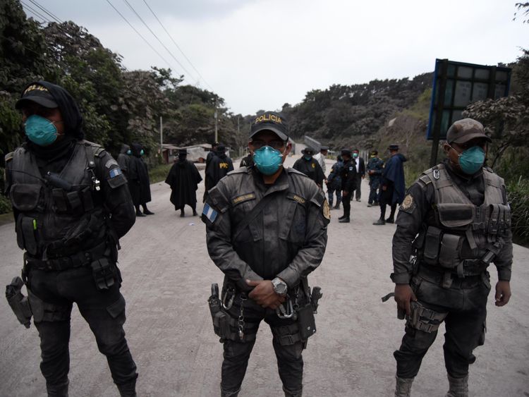 Police officers are posted, as the Fuego Volcano erupts