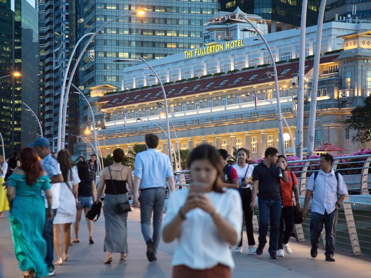 People walk on the Jubilee Bridge as the Fullerton Hotel stands in the background on June 4, 2018 in Singapore