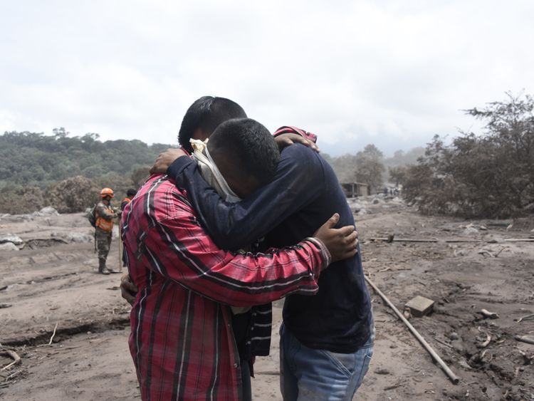 Guatemala volcano: Bryan Rivera, 22 (right), is comforted as he cries while searching for relatives, victims of the Fuego Volcano eruption in the ash-covered village of San Miguel Los Lotes, in Escuintla department