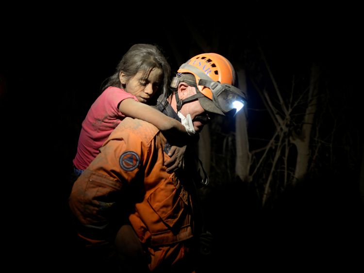 A rescue worker carries a child through the darkness to safety