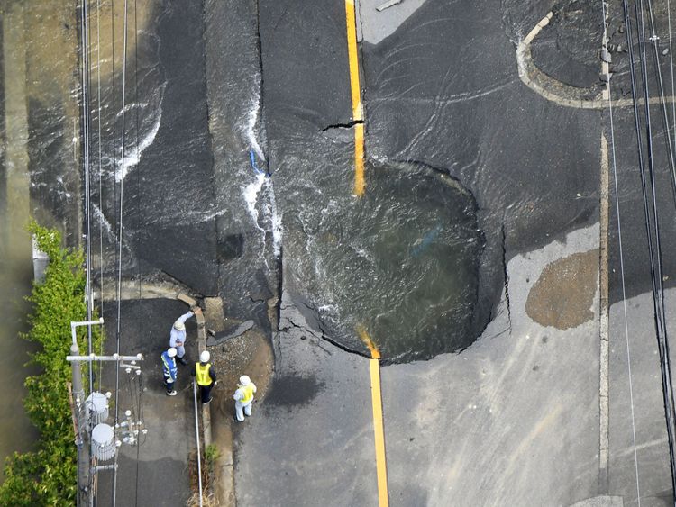 Water flows out from cracks in a road damaged by the earthquake