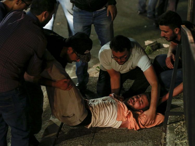 Jordanian protesters and security personnel tend to an unconscious man