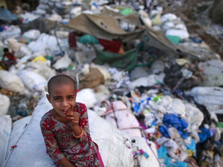 A girl sits among discarded rubbish in a Mumbai slum