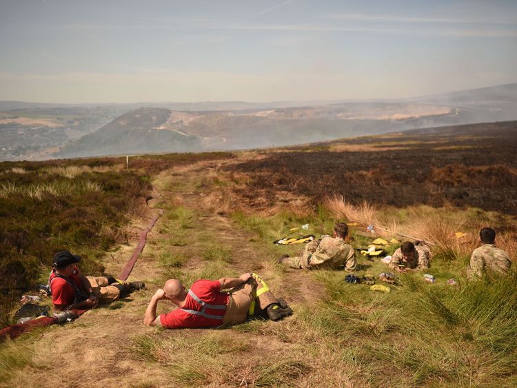 Firefighters and soldiers take a break from fighting a wildfire on Saddleworth moor near Stalybridge, northwest England on June 28, 2018