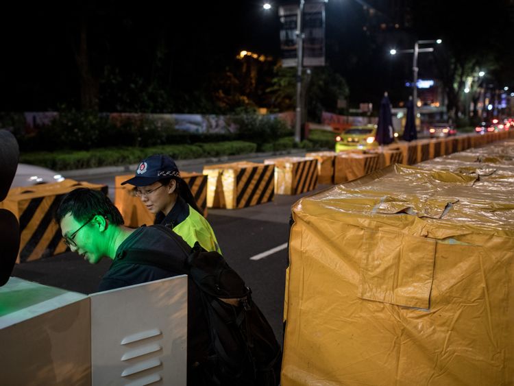 A man sets up an electronic security gate at a vehicle checkpoint in front of the St. Regis Hotel