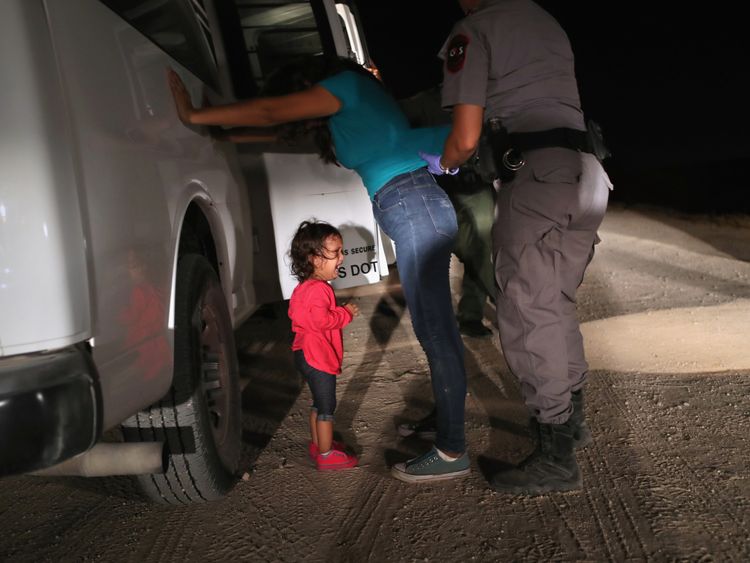 A toddler cries as her mother is searched at the border