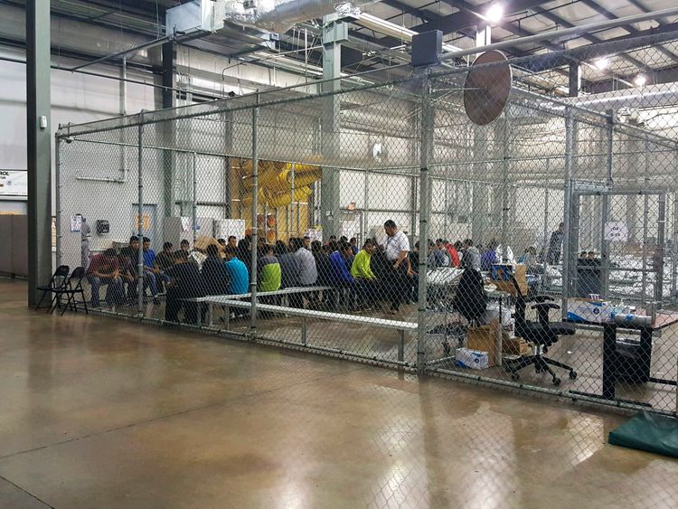 People sit on benches inside a cage in the facility