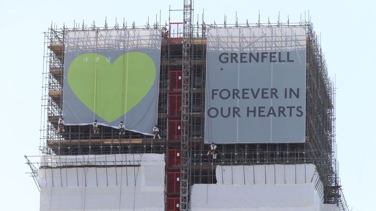 The banners being unfurled at the top of Grenfell Tower