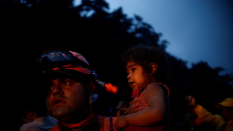 A rescue worker holds a little girl covered with ash following the eruption