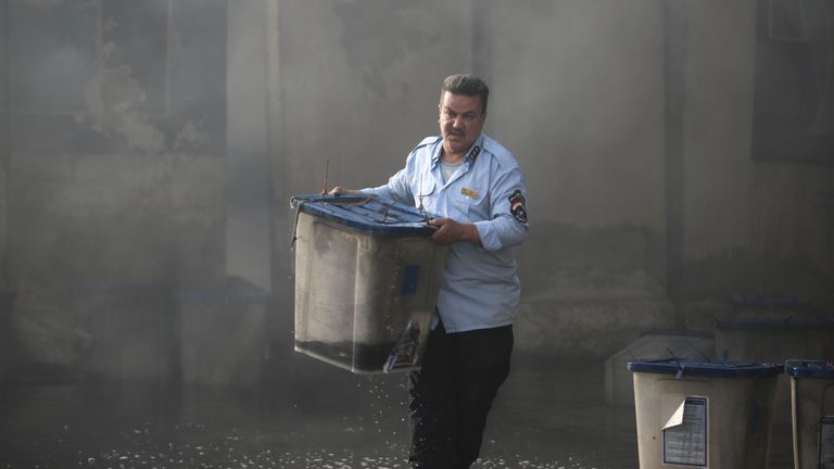 An official carries a ballot box after a fire at a storage site in Baghdad