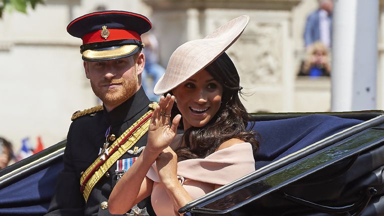 Meghan waves as she and Harry ride to Trooping the Colour