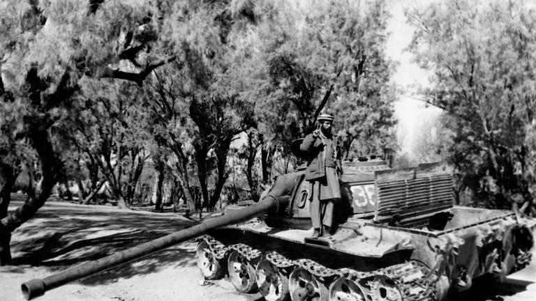A mujahideen fighter stands on a captured Soviet tank in February 1989