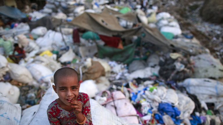 A girl sits among discarded rubbish in a Mumbai slum