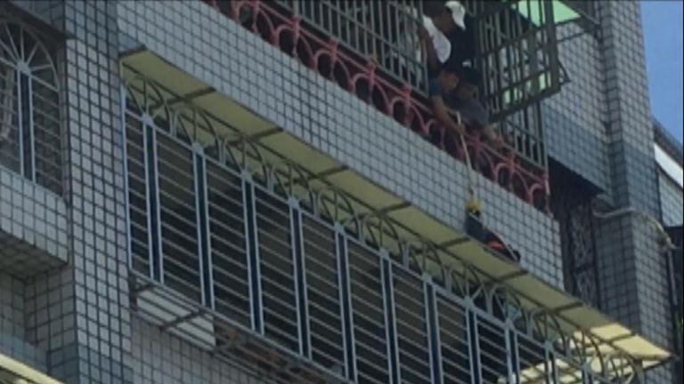 A four-year-old boy, who was left alone by his parents at home, was rescued after a half-hour ordeal of dangling through the security grille of a fifth-floor balcony 