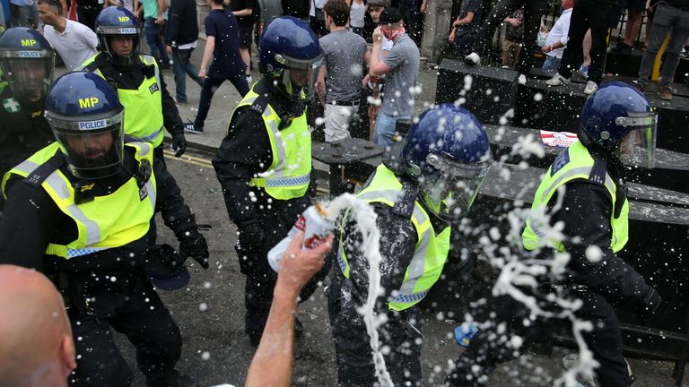 A man empties his beer over passing police at the junction of Whitehall and The Mall after a gathering by supporters of far-right spokesman Tommy Robinson turns to violent, in central London on June 9, 2018. (Photo by Daniel LEAL-OLIVAS / AFP) (Photo credit should read DANIEL LEAL-OLIVAS/AFP/Getty Images)
