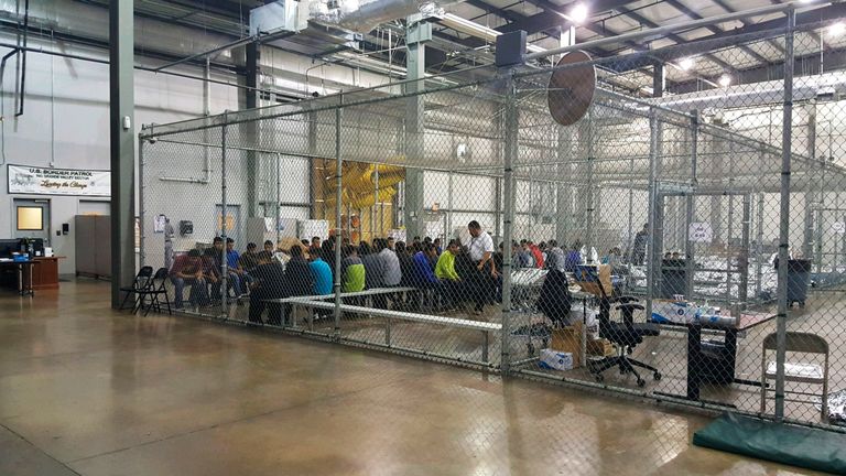 People sit on benches inside a cage in the facility